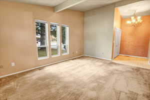 Carpeted spare room with a chandelier and a textured ceiling