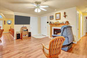 Living room featuring light wood finished floors, ceiling fan, and a tile fireplace