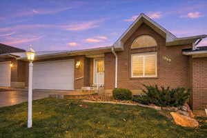 Ranch-style home featuring concrete driveway, a garage, a front yard, and brick siding