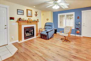 Sitting room with light wood-style flooring, a fireplace, and ceiling fan