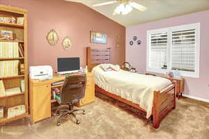 Bedroom with lofted ceiling, light carpet, ceiling fan, and a desk