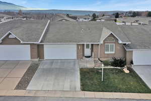 Ranch-style house with a shingled roof, brick siding, driveway, a residential view, and an attached garage