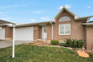 Ranch-style house featuring brick siding, driveway, a front lawn, and a garage