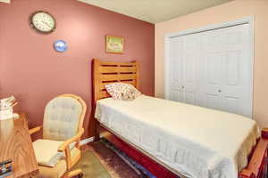 Carpeted bedroom with a closet and baseboards