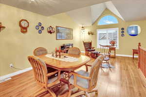Dining space with light wood-style floors and vaulted ceiling