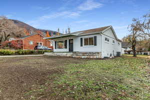 View of front of home featuring a front yard, a mountain view, brick siding, and a porch