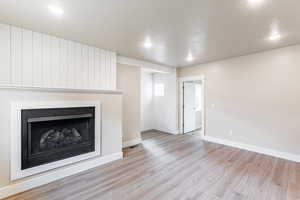 Family room featuring a fireplace, light wood finished floors, a textured ceiling, and recessed lighting