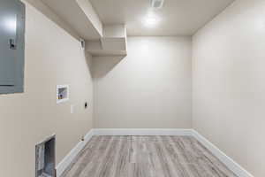 Utility/Washroom with light wood finished floors, electric panel, washer hookup, and electric dryer hookup