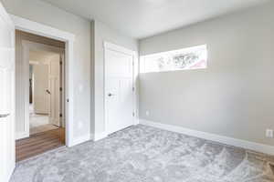 Bedroom with light carpet and baseboards.  Large window facing the street.