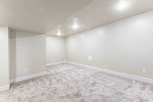 Basement family room with a textured ceiling and light colored carpet