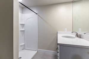 Basement bathroom featuring vanity, light tile patterned flooring, and a shower stall