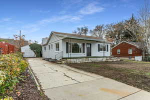 View of front of property with brick siding, a chimney, a garage, and covered porch
