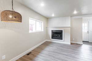 Family room with a large fireplace, a textured ceiling, light wood-style flooring, and recessed lighting