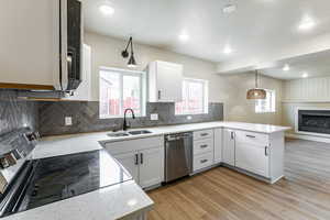 Kitchen featuring appliances with stainless steel finishes, a peninsula, backsplash, healthy amount of natural light, and a textured ceiling