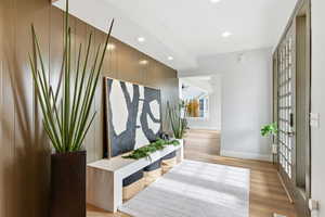 Corridor with an accent wall, recessed lighting, light wood-style flooring, and wood walls
