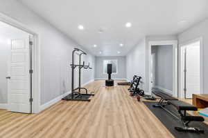 Exercise area with recessed lighting and light wood-style floors