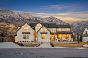 View of front of property with a mountain view, a balcony, stone siding, and a patio area