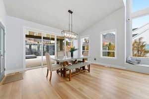 Dining room featuring vaulted ceiling, healthy amount of natural light, light wood-type flooring, and a chandelier