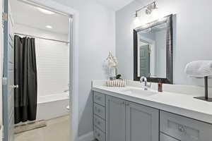 Full bath with vanity, shower / bath combination with curtain, and light tile patterned flooring