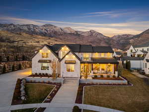 Back of property at dusk featuring stone siding, a porch, a mountain view, and driveway