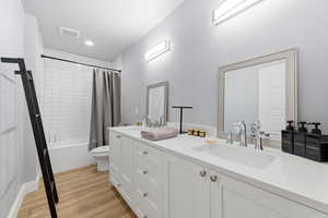 Full bathroom with shower / bath combination with curtain, double vanity, and light wood-style flooring