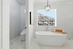 Bathroom featuring light marble finish flooring and a soaking tub