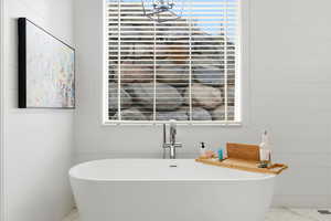 Bathroom with a freestanding bath and marble finish flooring