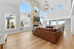 Living room with a fireplace, light wood finished floors, a chandelier, and plenty of natural light