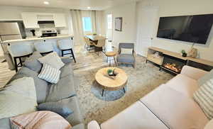 Living room featuring light wood-type flooring, recessed lighting, and a glass covered fireplace