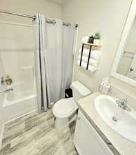 Full bath with vanity, shower / bath combination with curtain, and light wood-type flooring