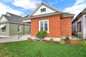 View of side of home featuring brick siding, a yard, and a shingled roof