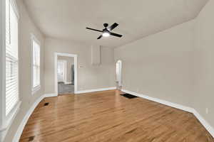 Spare room featuring arched walkways, light wood-type flooring, and a ceiling fan