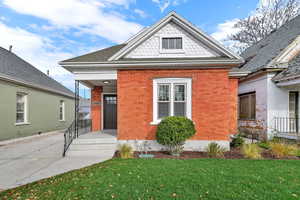 View of front facade with brick siding, a front yard, and roof with shingles