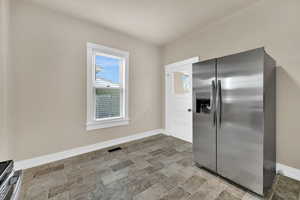 Kitchen with stainless steel refrigerator with ice dispenser and baseboards