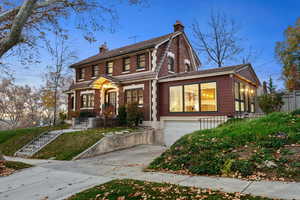 View of front of property with a chimney, brick siding, concrete driveway, and a garage