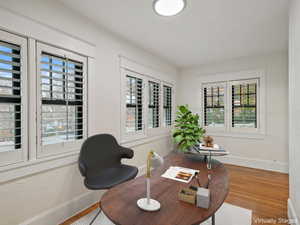 Sitting room with healthy amount of natural light, a desk, wood finished floors, and a textured wall