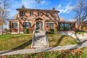 View of front of house featuring a chimney, brick siding, and a front yard