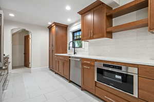 Kitchen featuring arched walkways, backsplash, open shelves, light tile patterned flooring, and recessed lighting