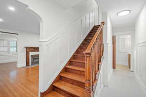 Staircase featuring a decorative wall, arched walkways, a fireplace, recessed lighting, and tile patterned floors