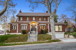 View of front facade featuring a chimney, brick siding, driveway, and a garage