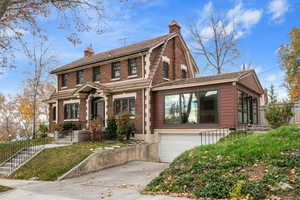 View of front of house with a chimney, a gambrel roof, brick siding, and concrete driveway