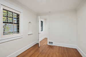 Empty room featuring wood finished floors and crown molding