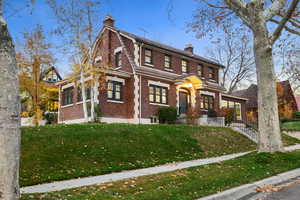 View of front facade featuring a chimney, brick siding, and a front yard