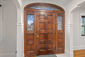 Foyer featuring arched walkways, ornamental molding, and wood finished floors