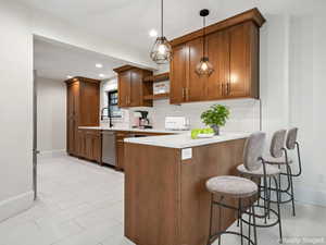 Kitchen featuring open shelves, a kitchen bar, a peninsula, decorative backsplash, and brown cabinetry