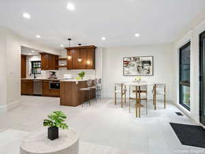 Kitchen with decorative light fixtures, open shelves, backsplash, stainless steel appliances, and a breakfast bar area