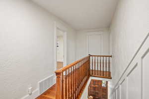 Stairway with a textured wall and wood finished floors