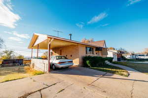 View of front of house featuring driveway, an attached carport, and brick siding