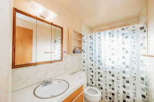 Full bathroom featuring a shower with shower curtain, vanity, and tile walls