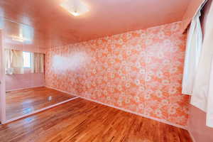 Unfurnished room featuring light wood-style flooring and wallpapered walls